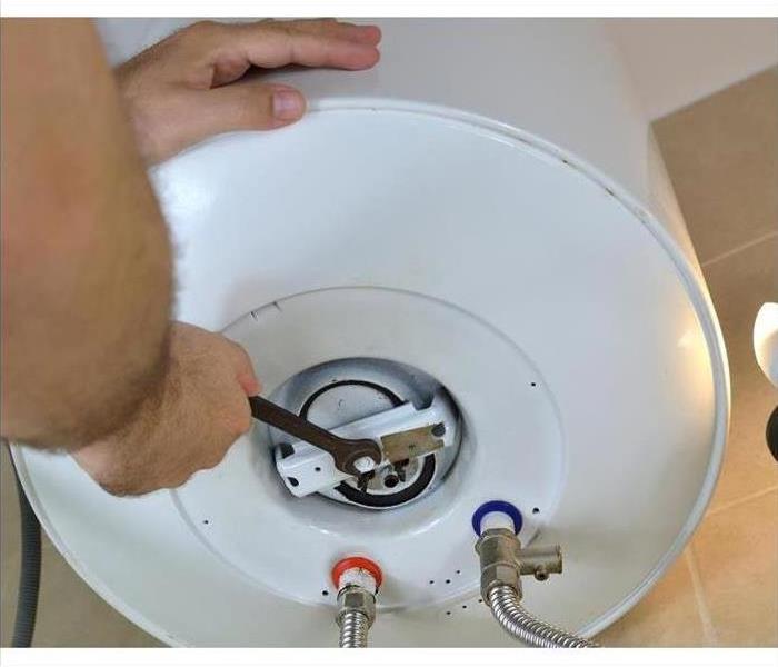 man using a tool on a white water heater